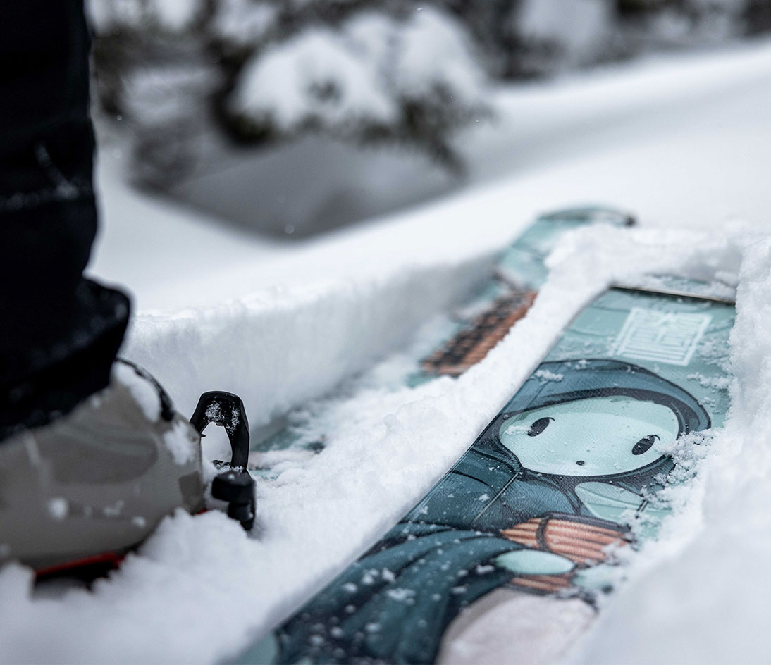 ARV JJ-UL details — Kodama artwork in the snow. Close-up of a ski boot on the ARV JJ-UL featuring Mike Shankster’s Kodama illustration in fresh snow.