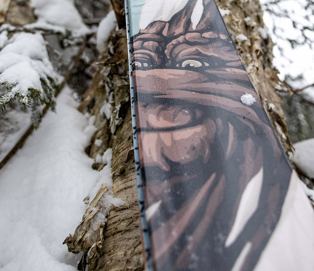 Tree spirit illustration detail from the ARV JJ-UL graphic package. Close-up of the tree spirit illustration on the ARV JJ-UL ski against a snowy tree.