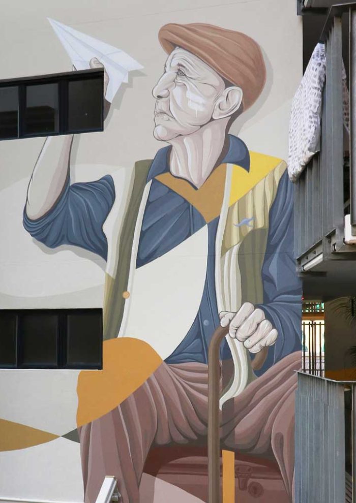 Warry Street Brisbane mural of an elderly man holding a paper plane and cane, painted on a building wall
