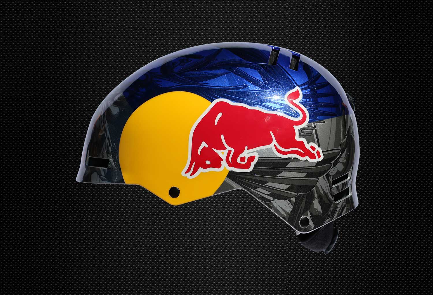 mike-shankster-redbull-russ-henshaw-side Side view of a Red Bull helmet with yellow circle and red bull icon over deep blue and grey custom graphic design on a black textured background.