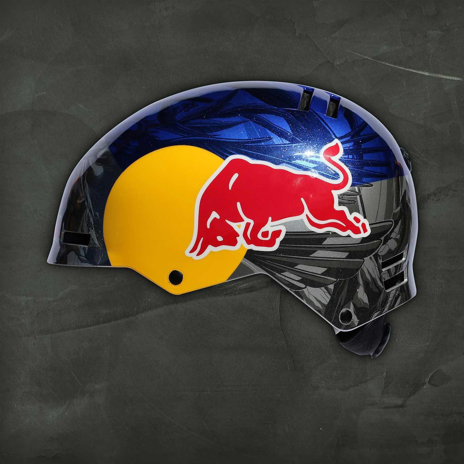 Red Bull helmet with custom blue and black graphic design, photographed on a dark textured background.