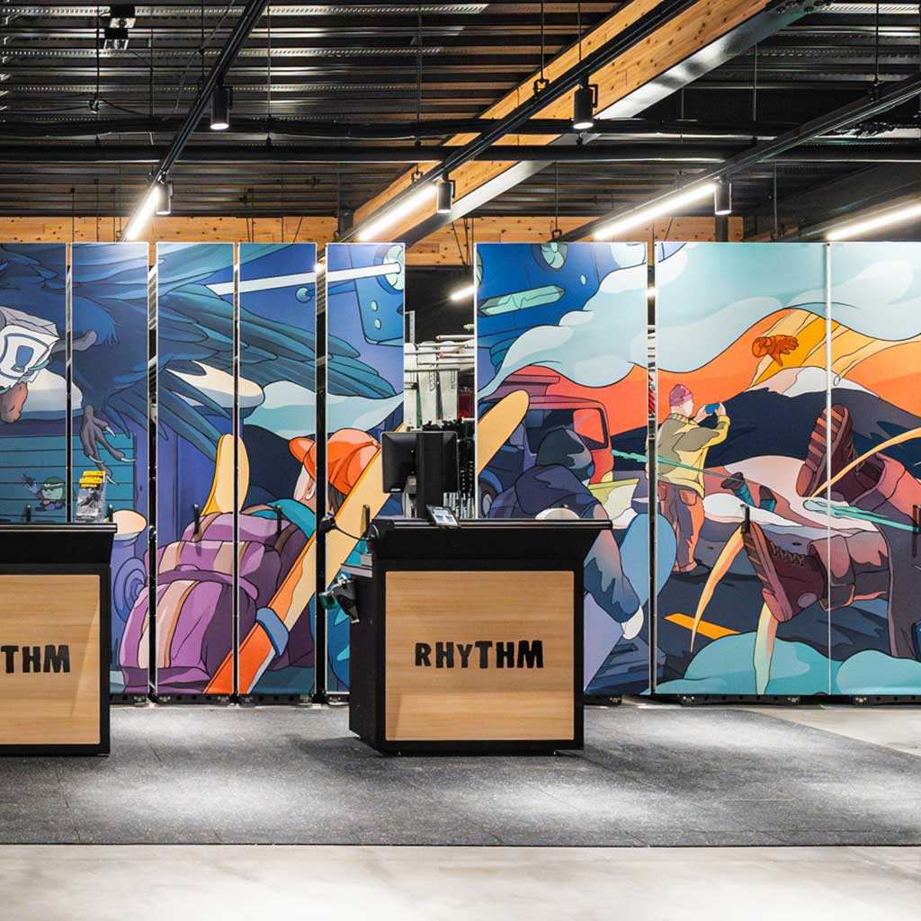 Illustrated in-store banner panels behind Rhythm checkout counter, showing snow travel scenes, mountains, and riders