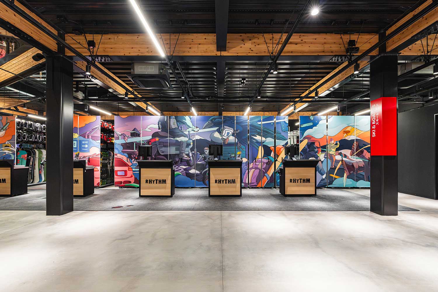 Wide view of Rhythm Japan store checkouts with illustrated banner panels across the back wall, timber ceiling and black steel fit-out