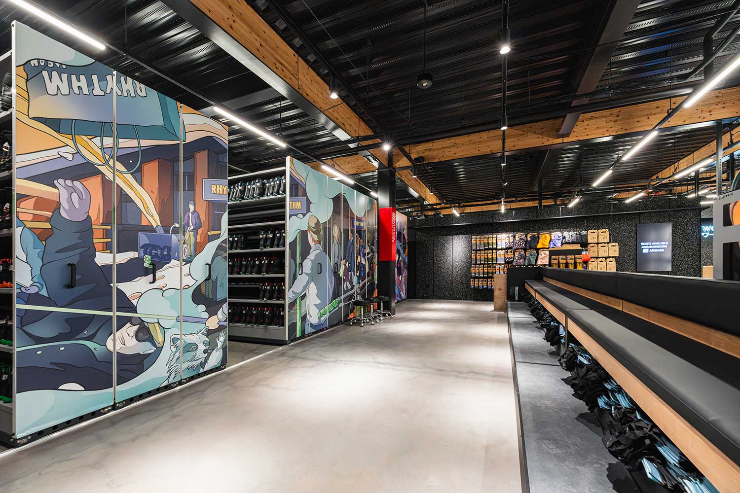 Rhythm Japan store aisle with long bench seating and illustrated banner panels on sliding rack storage along the left