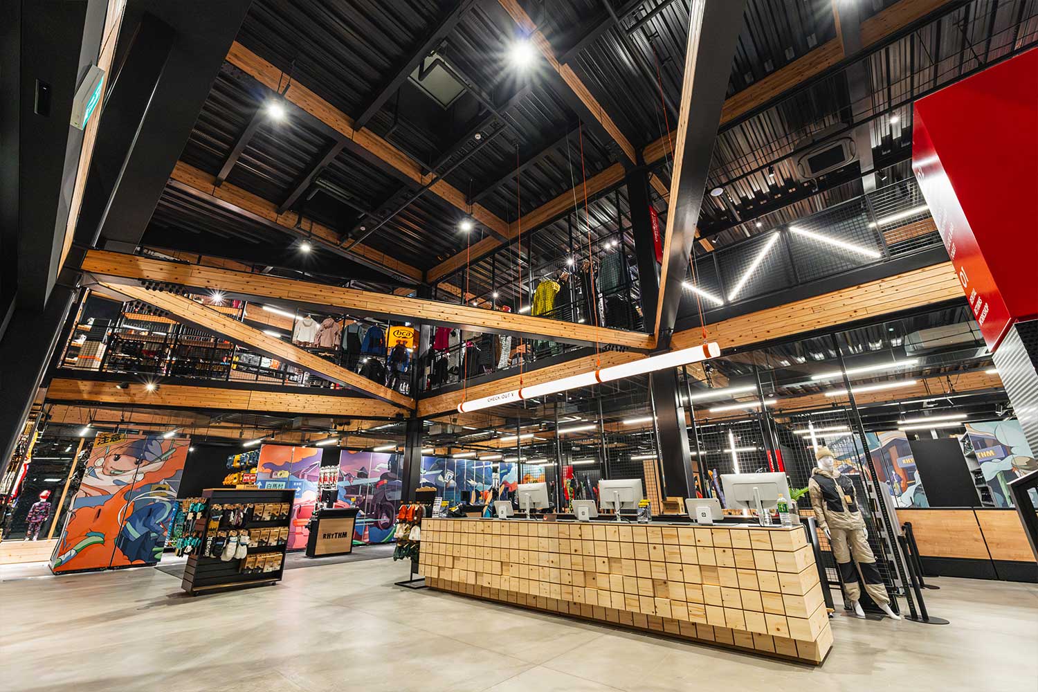 Wide interior of Rhythm Japan store with high timber ceiling, mezzanine, service counter, and illustrated banner panels throughout