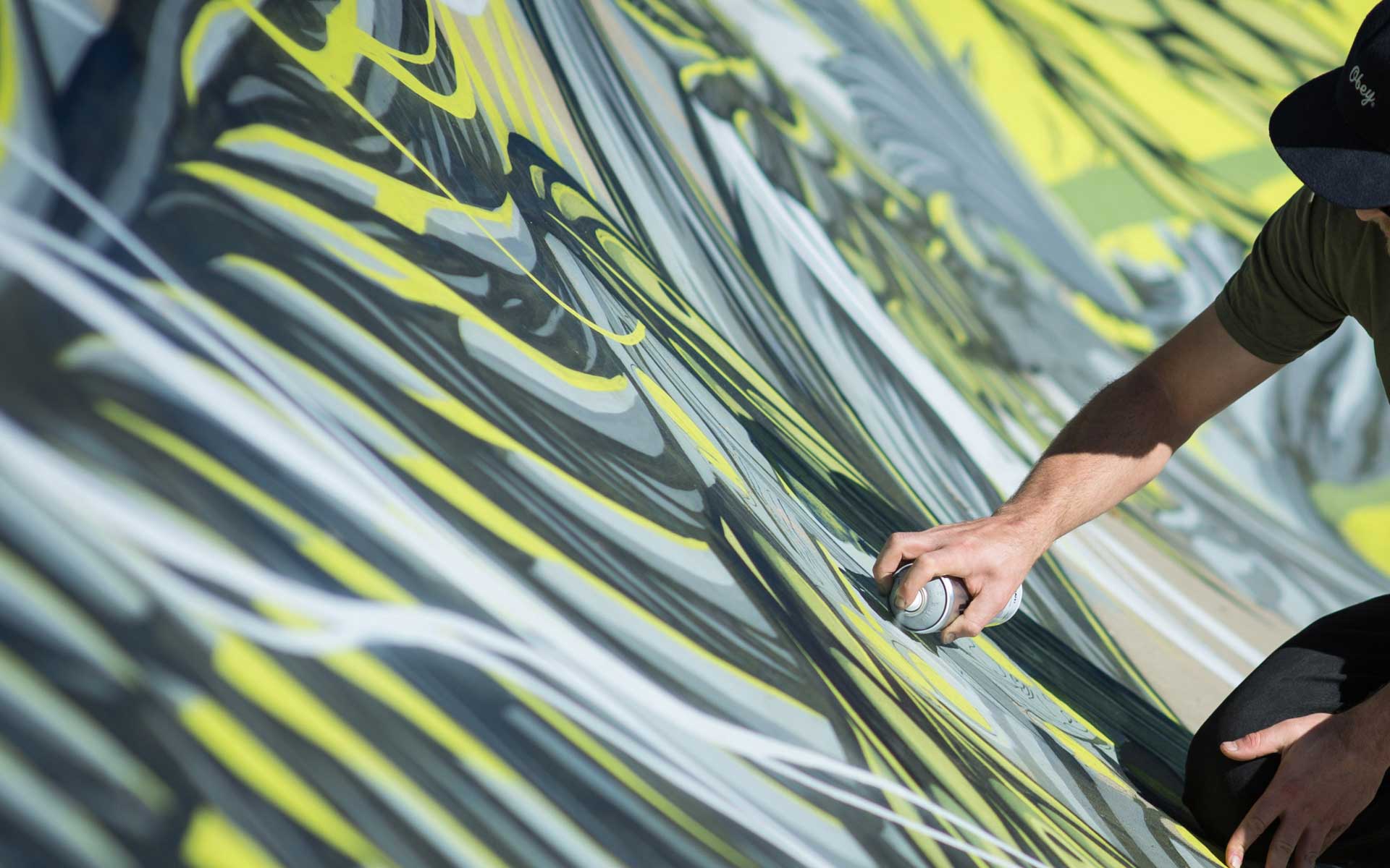 Gold Coast mural artist spray painting detailed street art on large exterior wall