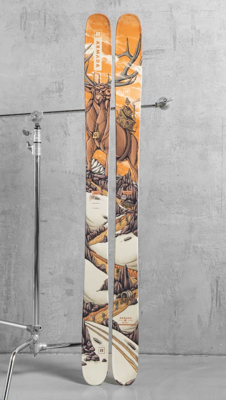 Full-length view of Armada skis featuring custom elk illustration artwork, with antlers, mountain landscape, cabin details, and orange sky across both skis.