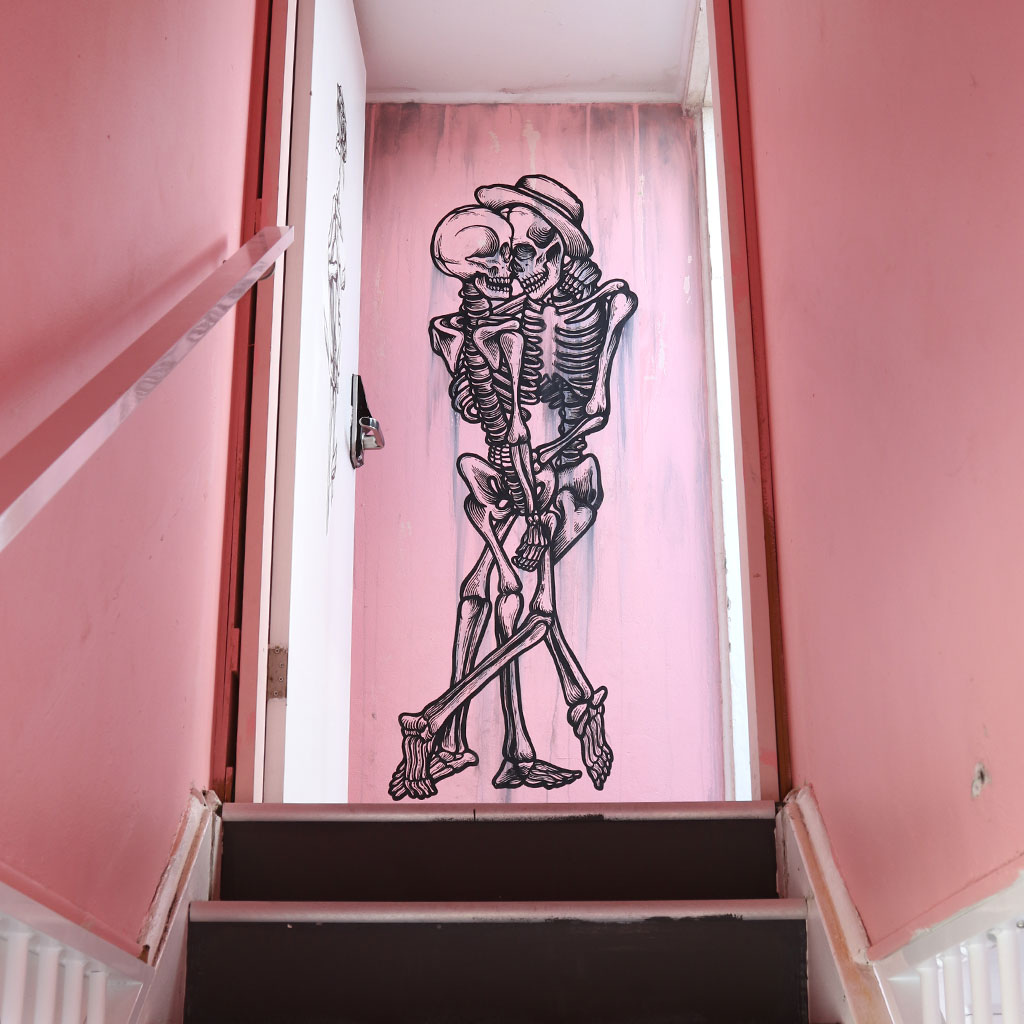Skeleton lovers mural painted in a doorway at The Pink Hotel in Coolangatta on the Gold Coast by Mike Shankster.