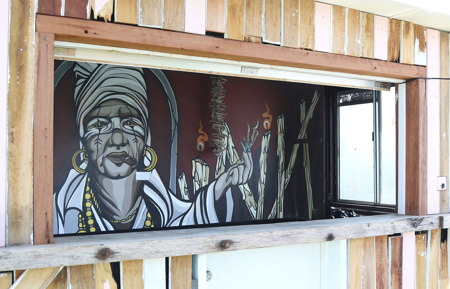 Cuban voodoo-inspired mural painted behind the rooftop bar at The Pink Hotel in Coolangatta, featuring a stylised figure, candles, and ritual imagery.