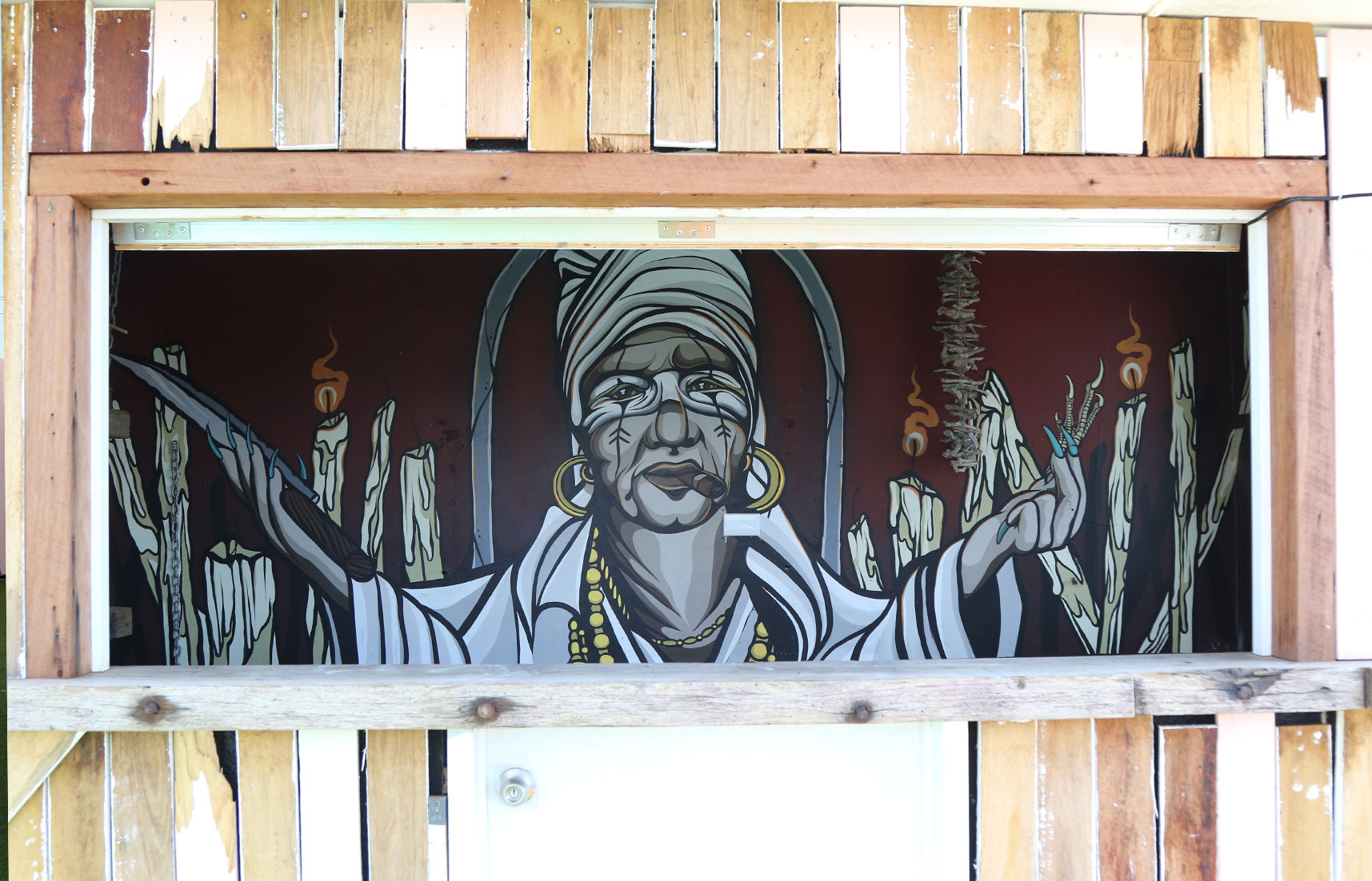 Full Cuban voodoo-themed mural behind the rooftop bar at The Pink Hotel, featuring a stylised figure, candles, and symbolic imagery.